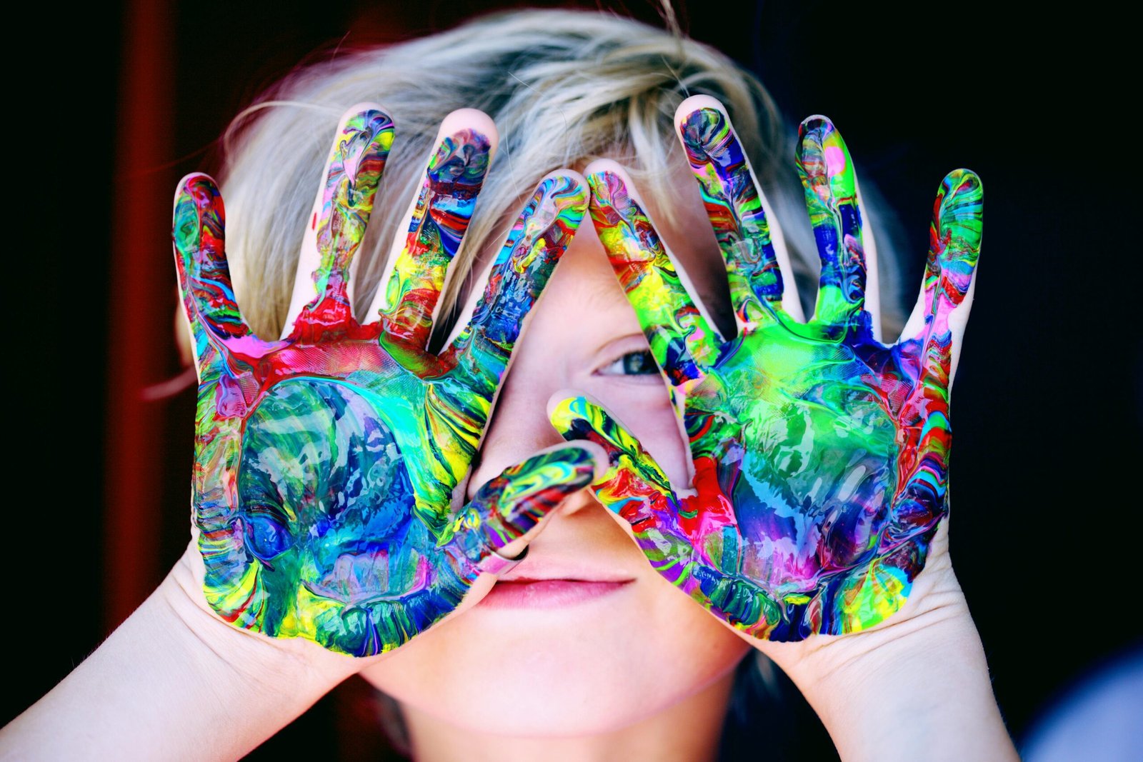 Manos cubiertas de pintura de varios colores.